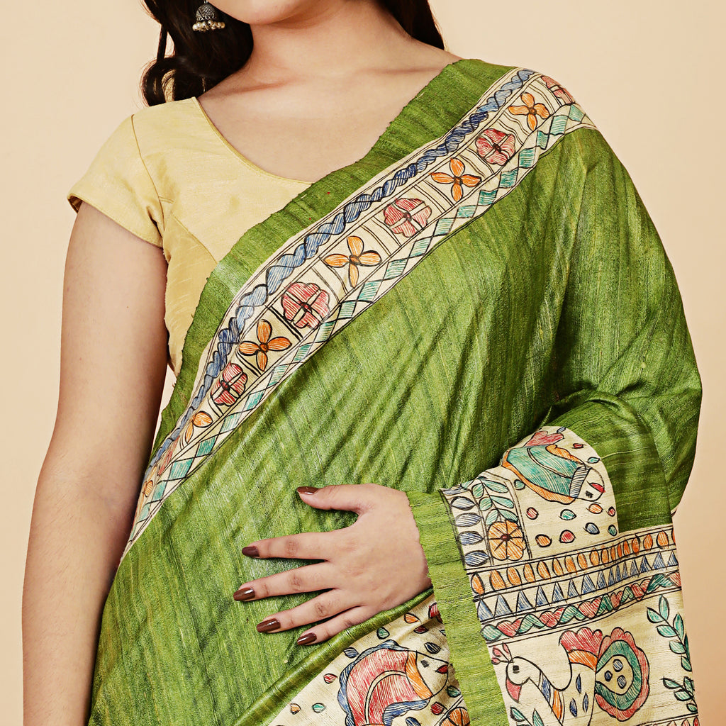 Woman wearing a green saree with colorful patterns on a beige background